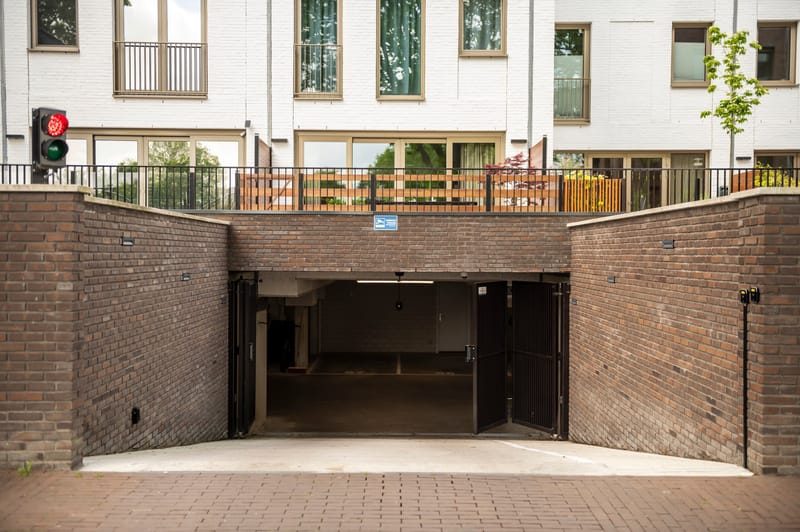 Inrit van een parkeergarage onder een appartementencomplex, met verkeerslicht