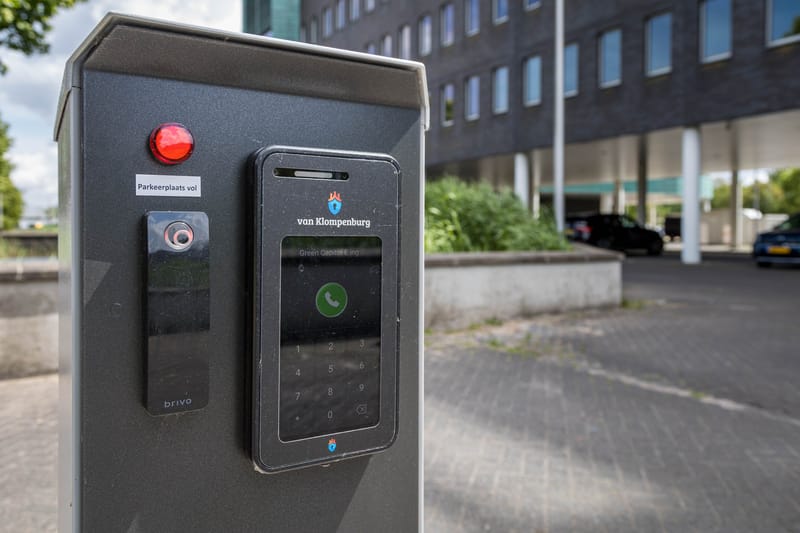 Intercom met camera en belknop op een toegangszuil bij een parkeerterrein